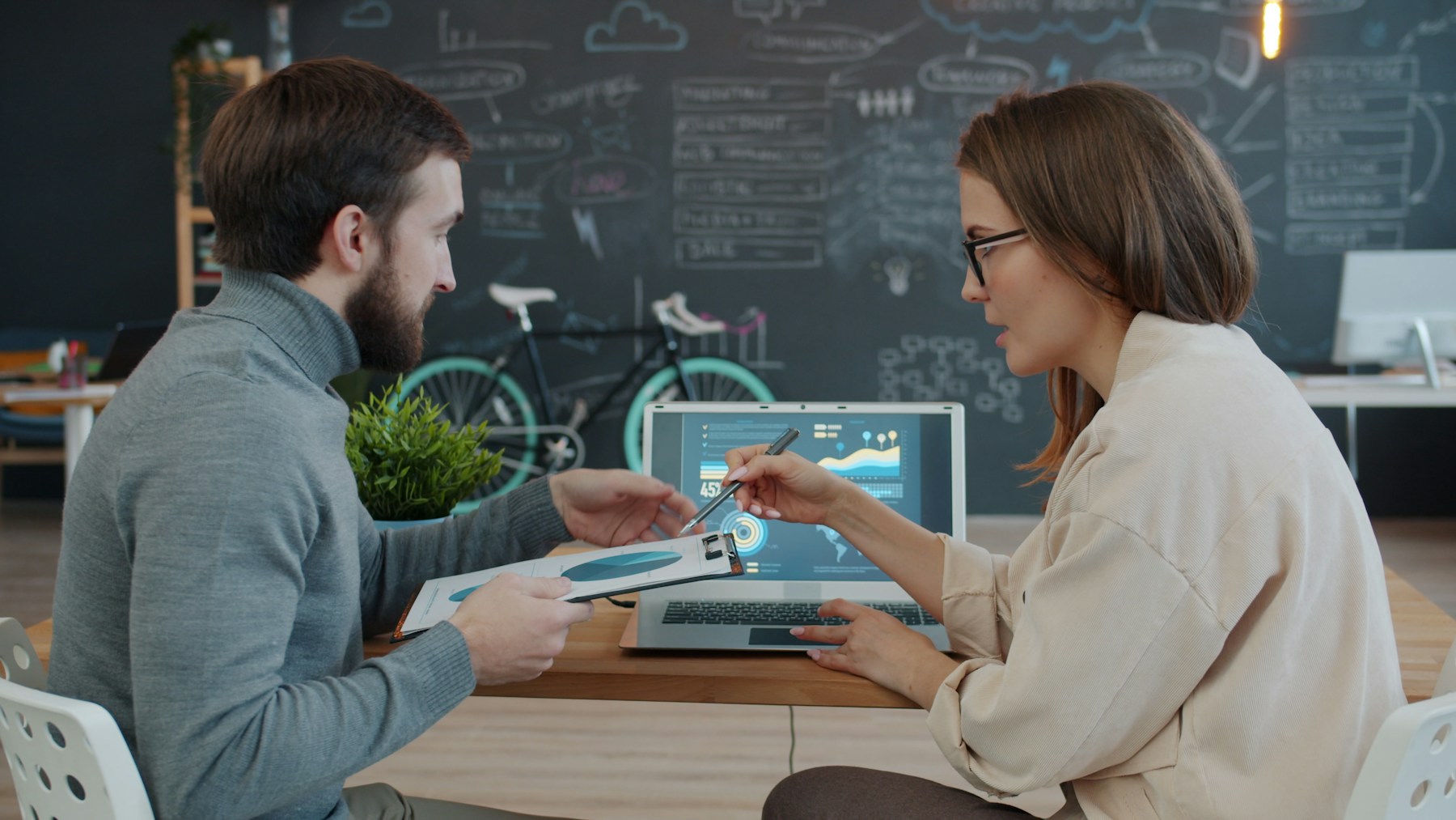Two colleagues reviewing work together on a laptop